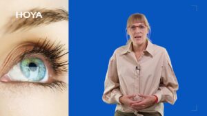 Kobieta tłumaczy temat wady wzroku na niebieskim tle, obok zbliżenie oka z logo Hoya.
