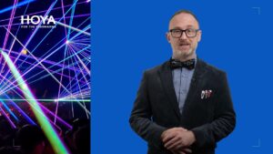 Mężczyzna w okularach i muszce na tle niebieskiego ekranu, obok grafika z neonowymi laserami.