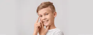 Chłopiec z uśmiechem w białej koszulce wskazuje na swoje oko, promując świadomość wad wzroku u dzieci.